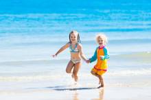 Two children playing in the turquoise water on their Emerald Coast vacation